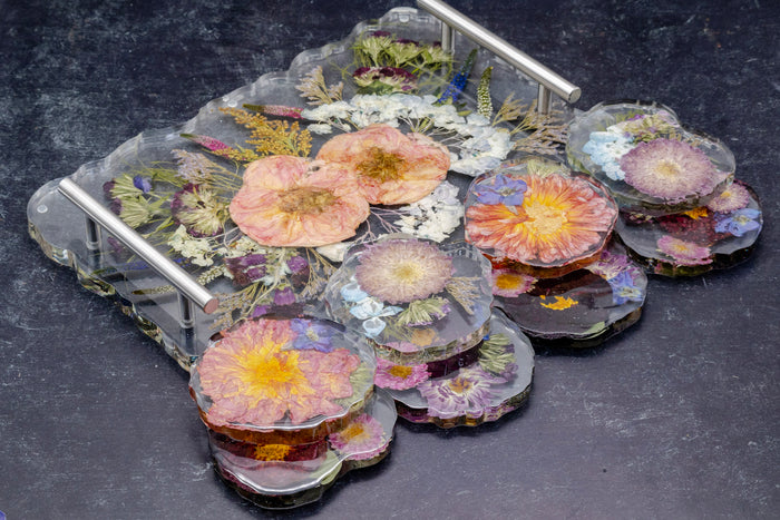 Landscape photo of a pressed flower serving tray and geode coaster set on a dark surface