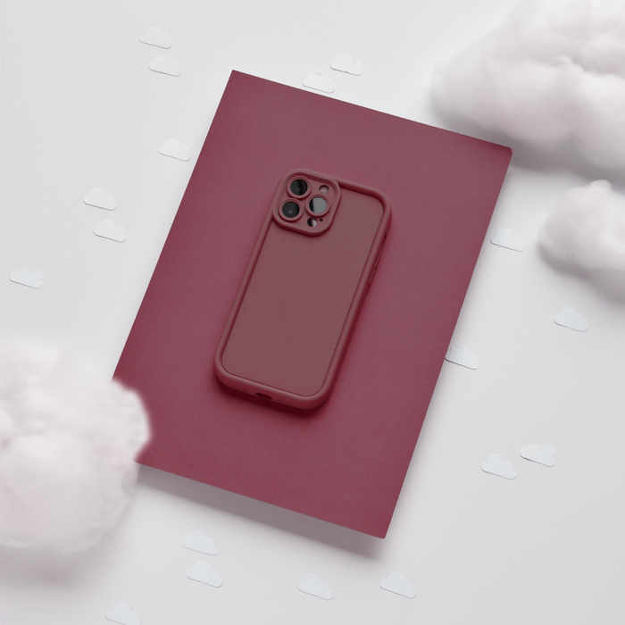 Burgundy Coconut Lane Cloud Soft NAKD Phone Case on a red notebook, surrounded by white cloud-shaped confetti.