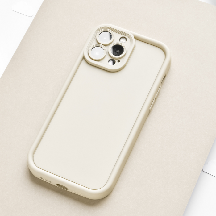 Beige smartphone in a Coconut Lane Cloud Soft NAKD cashmere cream case on a light tan surface.