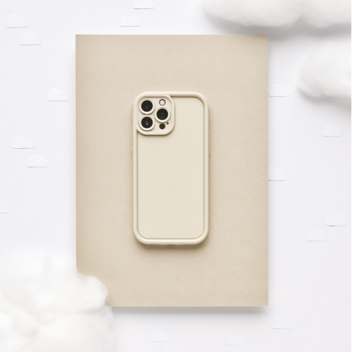 Pebble beige phone case with a soft finish on a tan notebook, surrounded by cotton and paper clouds.