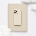 Pebble beige phone case with a soft finish on a tan notebook, surrounded by cotton and paper clouds.