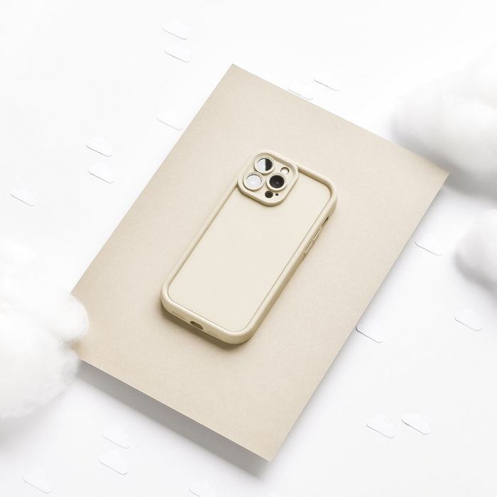 Pebble beige NAKD phone case with soft finish, shown on a beige background with cotton clouds and paper cutouts.