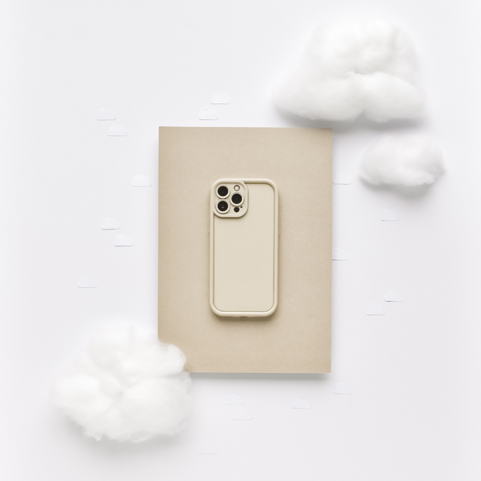 Pebble beige Coconut Lane Cloud Soft NAKD phone case displayed on a beige folder with fluffy white cotton clouds.