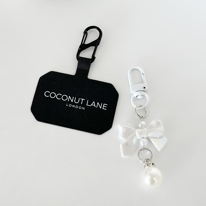 Iridescent phone keyring set with a decorative bow and pearl charm on a plain white background.