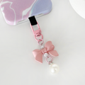 Peach pink bow phone keyring bundle attached to a purple and white swirl patterned phone case.