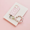 Pink and green crochet flower phone straps attached to a pink phone in a heart-patterned case.