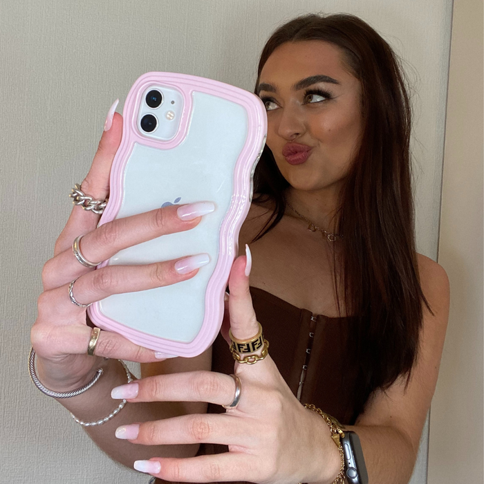 Young woman with long brown hair holds a pink Coconut Lane Curvy phone case while taking a selfie.