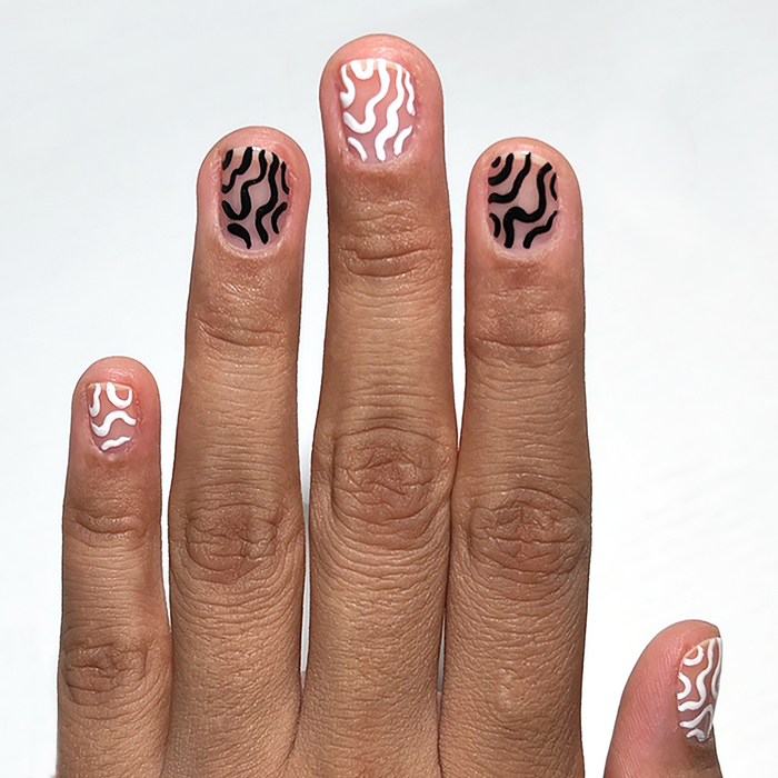Ink-redible black liner used for black and white squiggle nail art on a medium skin tone