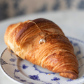 maman le croissant necklace resting on a croissant