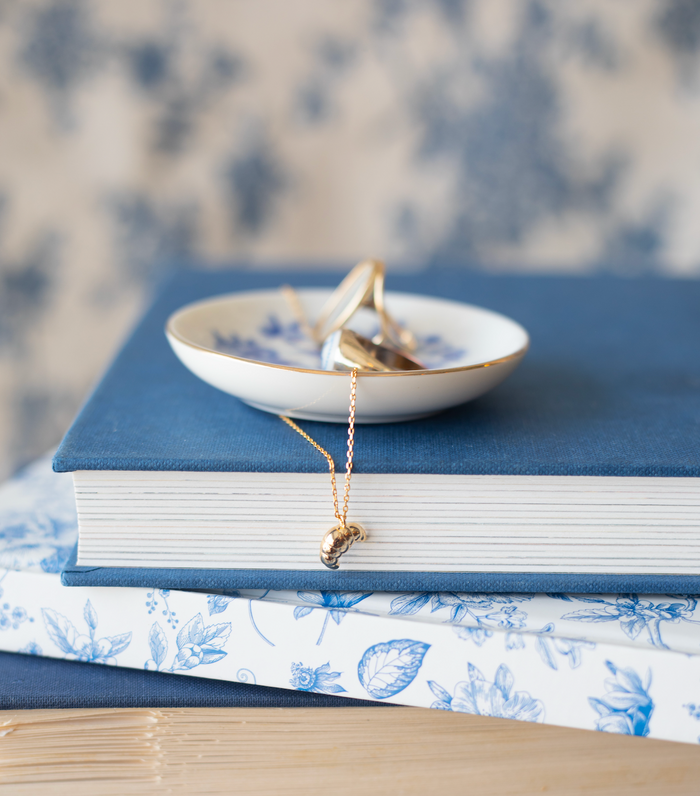 maman le croissant necklace hanging off a book