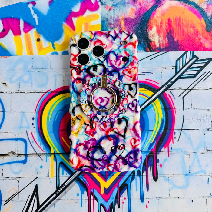 Love Out Loud colorful graffiti heart pattern MagSafe phone grip ring with overlapping neon pink purple and turquoise hearts compatible with iPhone and Samsung