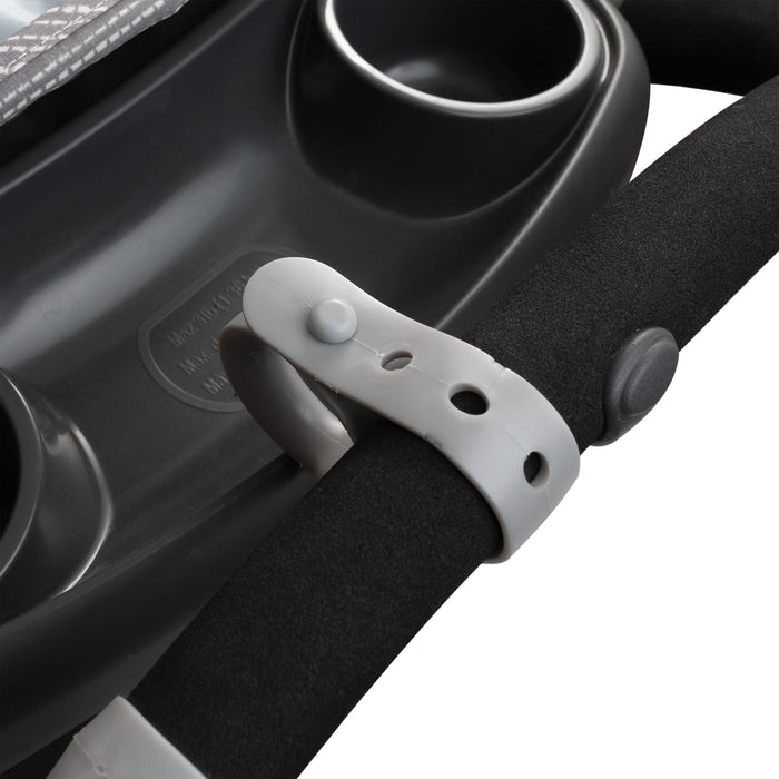Close-up of a black foam stroller handle with a white fastener beside a dark tray—ideal for attaching Nuby Non-Slip Stroller Hook (2 Pack) | Grey and other essential accessories for added convenience.
