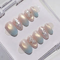 EyeCandys Pearl Jam Press-On Nails are glossy pale pink press-ons with a subtle iridescent sheen, white glitter accents, and a 3D bow for a chic pearl look, elegantly displayed in a clear case.