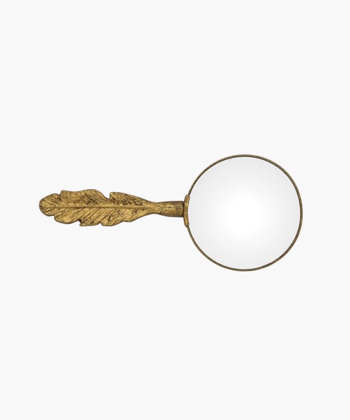 Vintage inspired magnifying glass with a distinct ornate handle shaped like a textured gold leaf or feather. The glass lens is clear, creating an elegant, antique feel. | SW Home