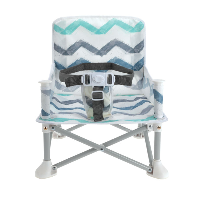 The Nuby Pop Up Booster Seat | Chevron features a blue, teal, and gray zigzag pattern, sturdy metal legs with white feet, a safety harness, and folds for portability—ideal as a travel high chair for families on the go.