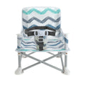 The Nuby Pop Up Booster Seat | Chevron features a blue, teal, and gray zigzag pattern, sturdy metal legs with white feet, a safety harness, and folds for portability—ideal as a travel high chair for families on the go.