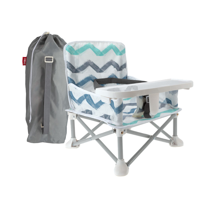 The Nuby Pop Up Booster Seat | Chevron features a chevron-patterned fabric, attached tray, and safety harness, and comes with a gray carrying bag—ideal as a portable travel booster seat for meals on the go.