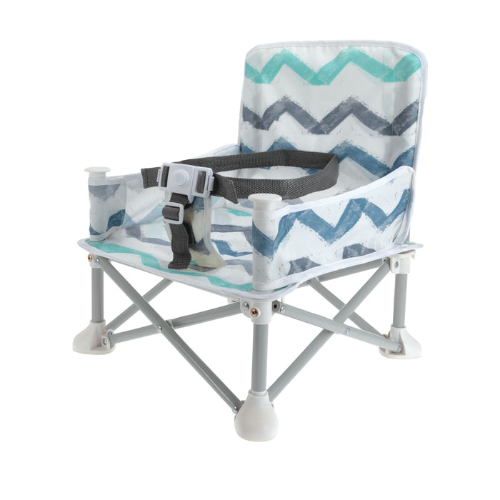 The Nuby Pop Up Booster Seat | Chevron features a gray, blue, and teal chevron pattern, safety straps, and white plastic feet—portable and foldable for toddlers on the go.