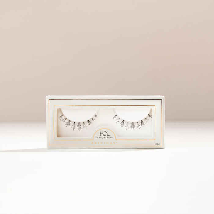 Precious lower lashes displayed in a white box with window on a light beige background.