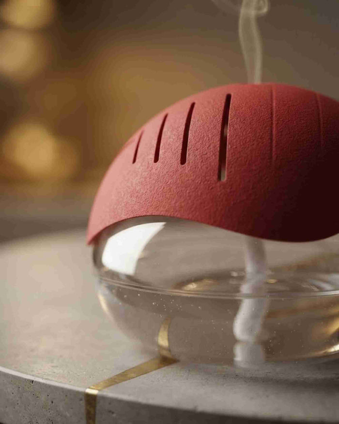 Red dome-top aroma diffuser close-up with visible mist flow