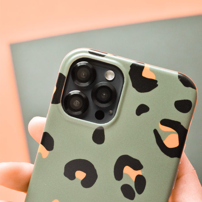 Smartphone in green and black leopard print case with black Coconut Lane camera lens covers held in a hand.
