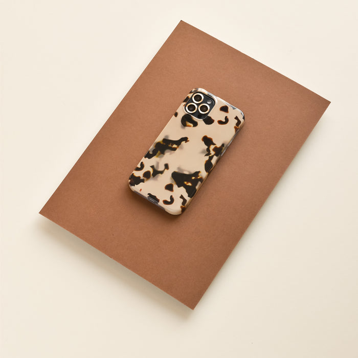 Phone with Coconut Lane gold camera lens covers in a beige and black case on brown paper.