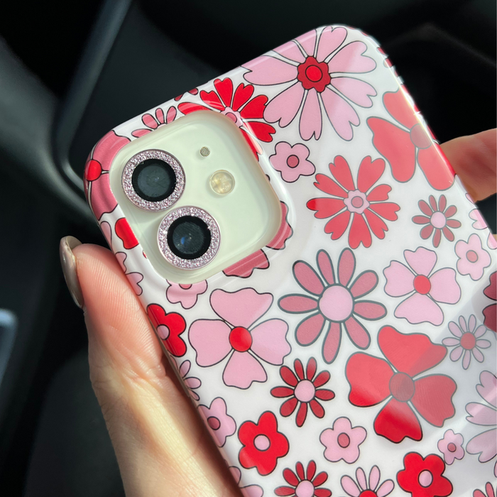 Hand holding an iPhone with a pink glitter Coconut Lane camera lens cover attached.
