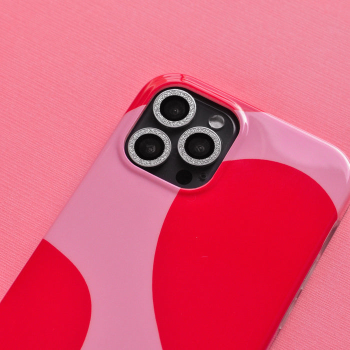 Smartphone with silver glitter camera lens covers by Coconut Lane on a pink textured surface.