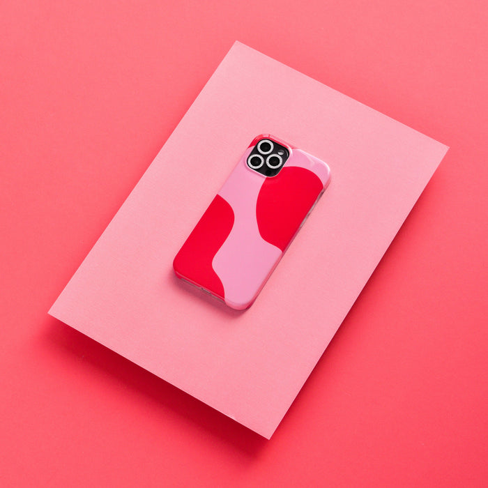 Silver glitter camera lens covers on a pink sheet next to a red and pink phone case.