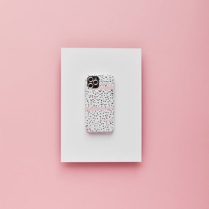 Smartphone with silver camera lens covers and a speckled case, displayed on a white board with a pink background.