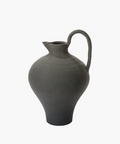 A gray pottery jug with a narrow spout, rounded body, and curved handle. The texture appears smooth, conveying an earthy, traditional feel. | Wildwood Home Co.
