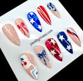Ten press-on nails with patriotic red, white, and blue designs, including stars, stripes, and bows, displayed on a white card with the text 'pawsbypicaso.com'.