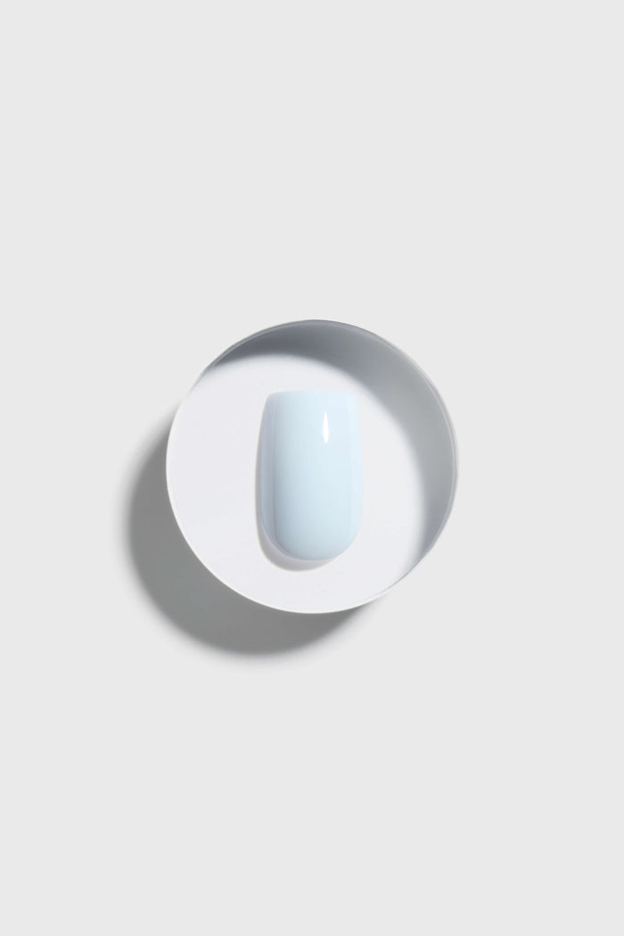 sky blue press-on nail on a white plate with a gray background