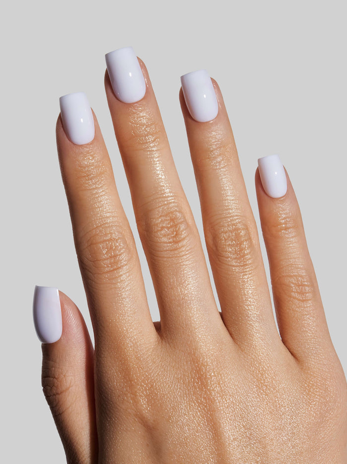 Close-up of a hand with sky blue press-on nails on a neutral background