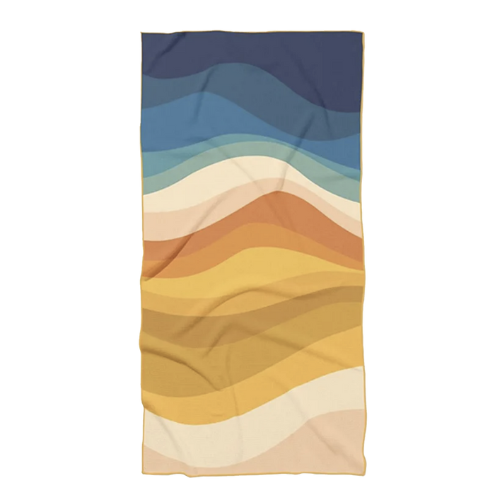 Soft beach towel with wavy gradient design in blue, beige, and gold tones, ideal for poolside or seaside relaxation.
