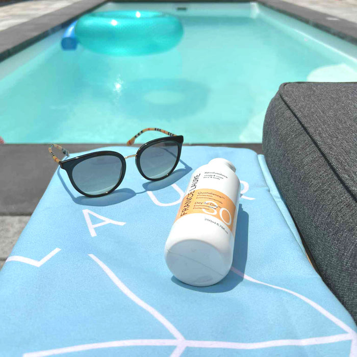 France Laure Day-to-Day SPF 30 sunscreen bottle and sunglasses on poolside towel, ideal for face & body sun protection