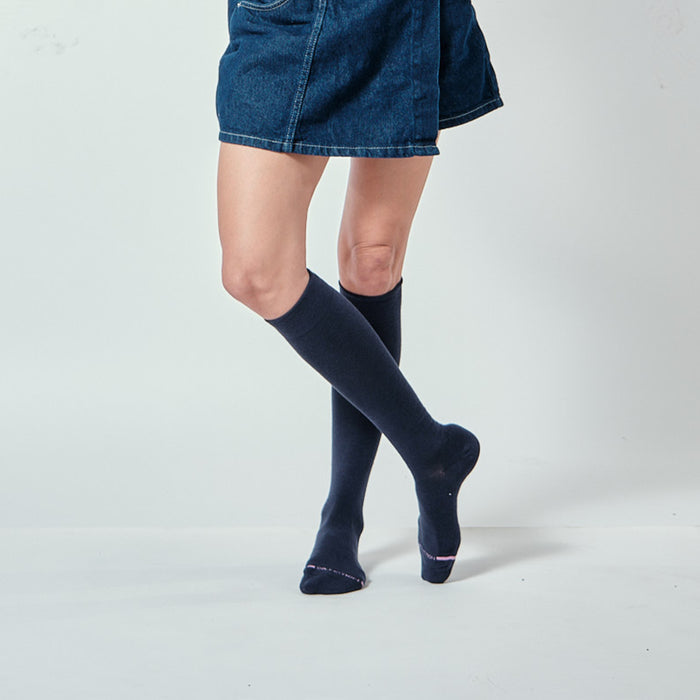 Knee-high compression socks in dark color worn with a denim skirt, showcasing the leg and sock design.
