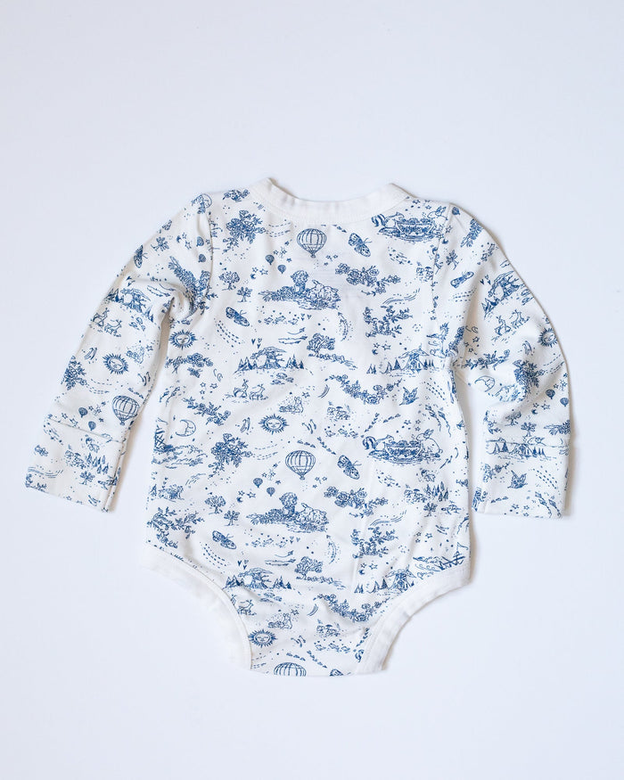 Blue-and-white toile bodysuit with flowers, bunnies, butterflies, hot air balloons, boats, moons, and suns.