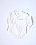 White muslin bodysuit with "mon petit chou" ("my little darling" in French) embroidered in blue on the chest.