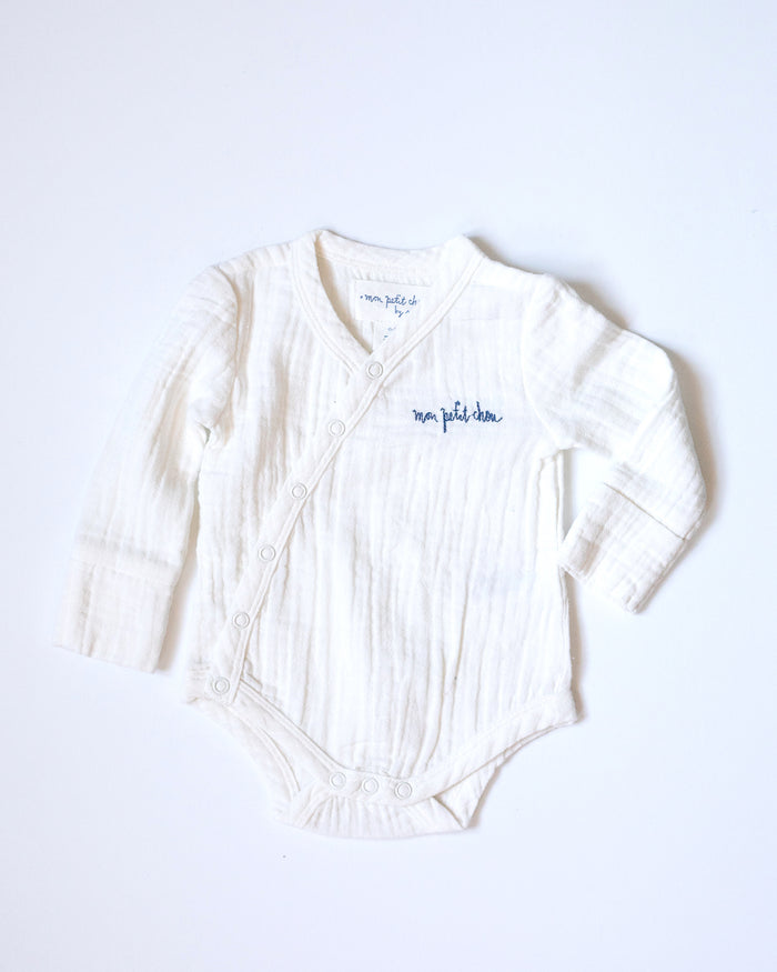 White muslin bodysuit with "mon petit chou" ("my little darling" in French) embroidered in blue on the chest.