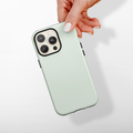 Hand holding a phone in a Coconut Lane NAKD Sage Tough MagSafe® case with triple rear camera lenses visible.