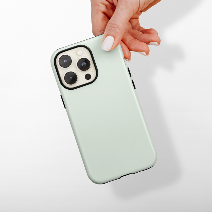 Hand holding a phone in a Coconut Lane NAKD Sage Tough MagSafe® case with triple rear camera lenses visible.