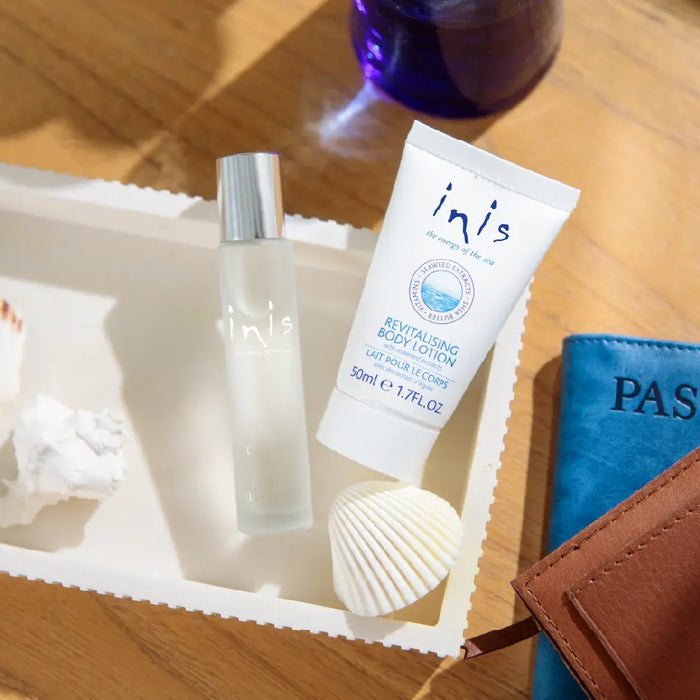 Inis skincare products on a wooden surface with a passport and shell.