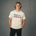 A young man wearing a light-colored t-shirt with a ’Planett’ graphic and dark pants.