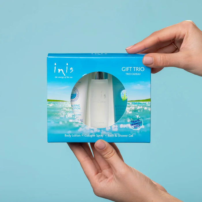Hand holding an 'inis' gift trio packaging against a light blue background