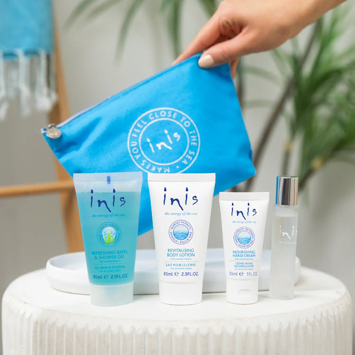 Inis skincare products including bottles and tubes on a white surface with a blue pouch.